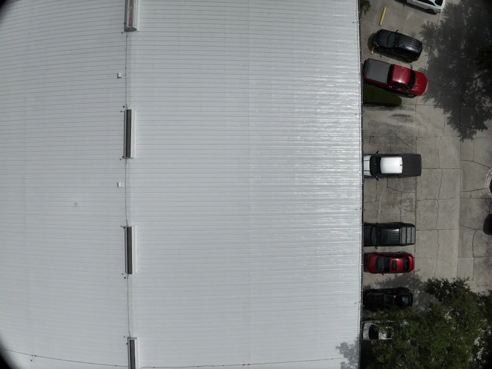 A later overhead record — A later capture of the metal roof layout and the adjacent parking area.