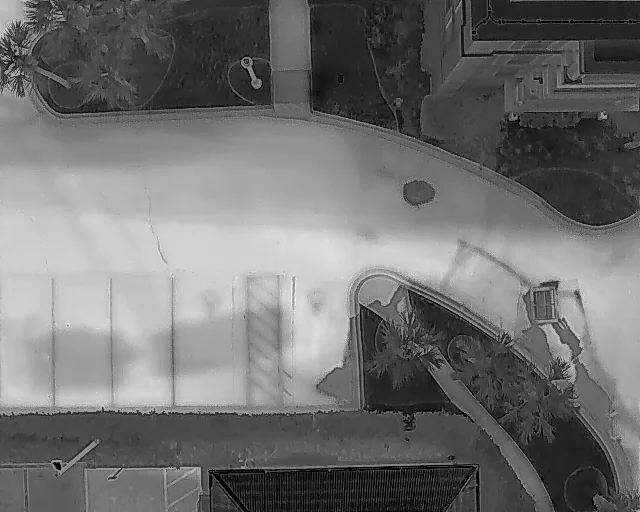 Thermal: roof and grounds — A grayscale thermal frame records apparent surface temperature patterns across a roof and its surroundings.