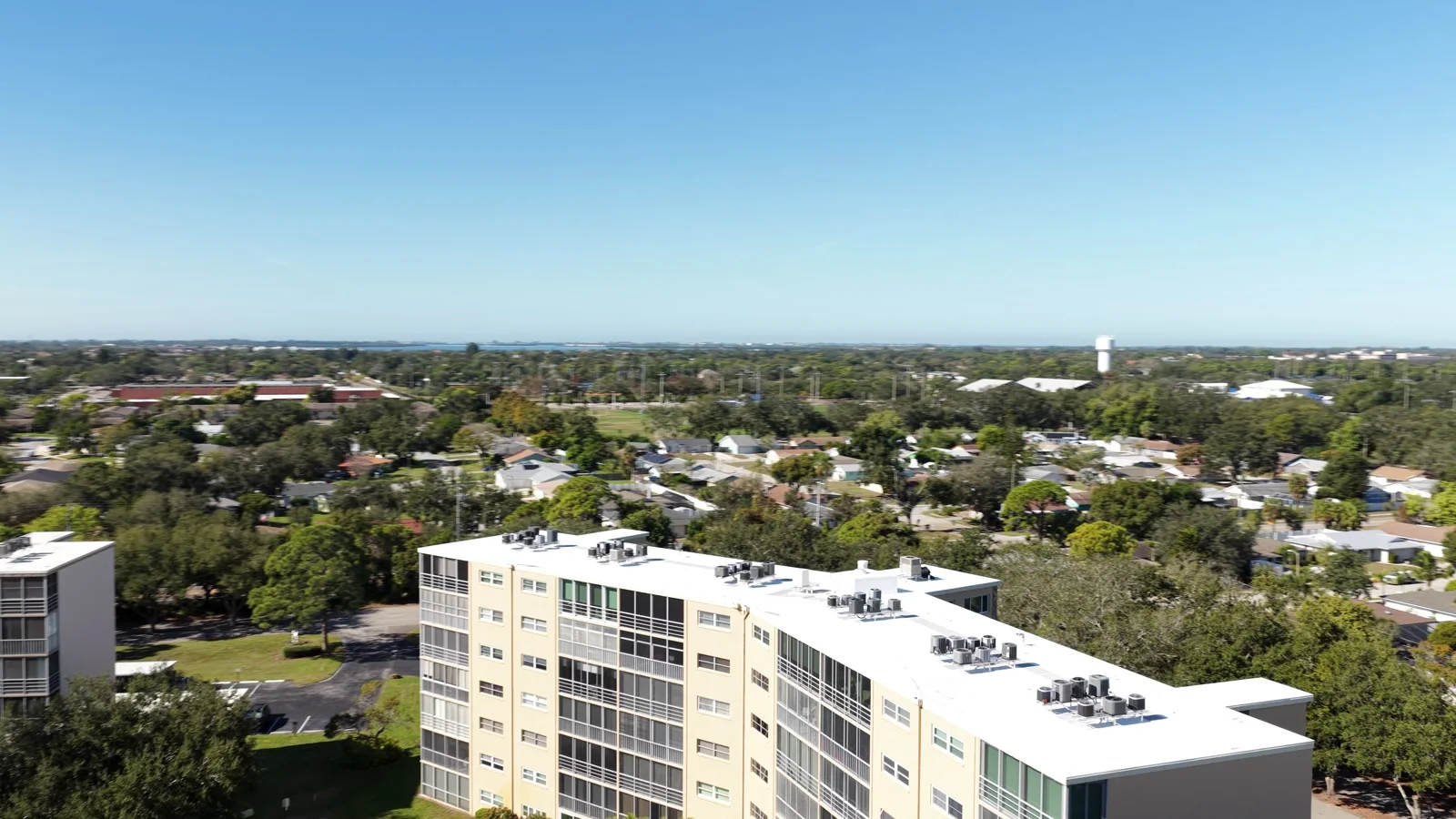 Aerial view of a flat-roofed condominium building and the neighborhood beyond