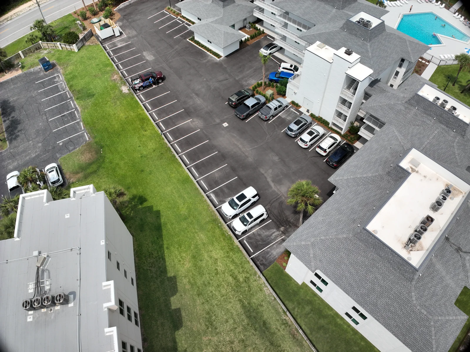 Angled aerial view of a condominium building wing beside a parking area