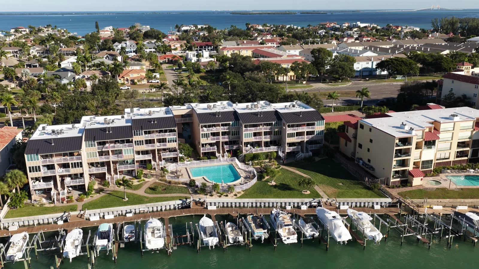 Waterfront condominium buildings, a swimming pool and boats docked along the shore